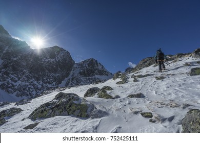 Climbers Ascending A Snowe Ridge To The Summit Of A High Peak. Blue Sky, Beautiful Clouds And Winter Mountians Around. Winter Hiking Adventure.