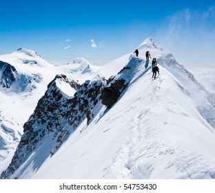 Climbers balancing in blizzard on a narrow ridge of Lyskamm (aka Maneater, 4480 m)