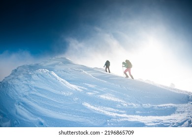 Climbers Climb The Mountain. Two Girls In Snowshoes Walk In The Snow. Hiking In The Mountains In Winter.