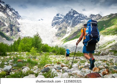 Climbers with hiking backpacks go to the mountain. hikers in mountains. Tourists hike on rocky mounts. Leisure activity on mountain trek in wild Svaneti region of Georgia. Groupe Hiking.