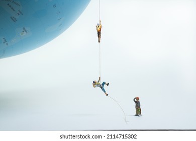 climbers pull themselves up on a rope to a globe