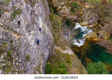 Climbers Scrambling Up A Rock Wall With Whitewater River In The Background.