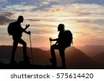climbers silhouette on top of a mountain at sunset