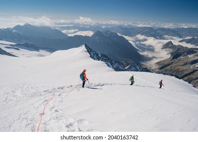 Climbers Team On A Trail Through A Dangerous Glacier And Avalanches In Austiran Alps. Epic Moment Near The Top Of Großvenediger Glacier As The Clouds Disappear For A Moment. 