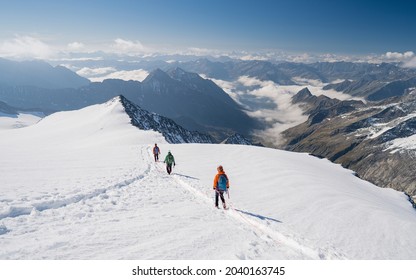 Climbers Team On A Trail Through A Dangerous Glacier And Avalanches In Austiran Alps. Epic Moment Near The Top Of Großvenediger Glacier As The Clouds Disappear For A Moment. 