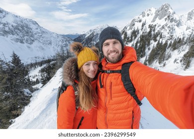 Climbing couple takes a selfie from a snowy landscape in the winter mountains