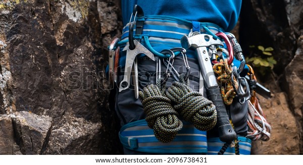 Climbing\
equipment, ropes, carabiners, harness, belay, hammer close-up of a\
rock-climber put on by a man, the traveler leads an active\
lifestyle and is engaged in\
mountaineering.