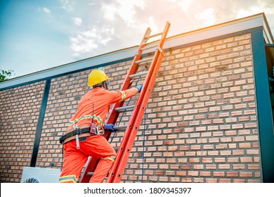 Climbing The Risks Of A Worker By Ladder To Work On The Roof Of A House On A Beautiful Sunny Day.