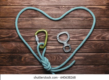 Climbing Rope In The Shape Of A Heart With Carbine On Wooden Background, Top View.