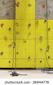  Climbing Simulator ,Fit Man Looking Up At Rock Climbing Wall At The Gym, Yellow Concrete Wall Background And A Carabiner Hook.