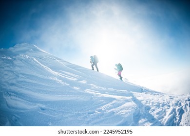 climbing a snow-covered mountain during a snow storm, two women in winter trekking, climbers climb to the top of the mountain in winter - Powered by Shutterstock