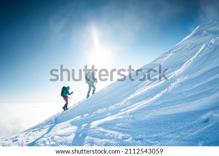climbing a snow-covered mountain, two women in winter trekking, climbers climb to the top of the mountain in winter