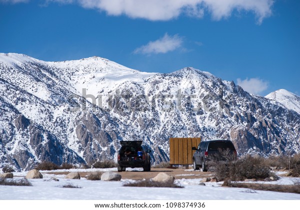 The climbing\
spot Buttermilk Area near Bishop, California. Snow peaks and\
boulders. Cars on the parking\
place.