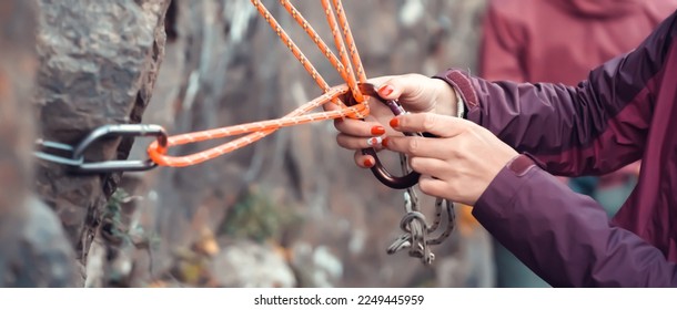 Climbing station on bolts on a rock, people are learning mountaineering in a camp outdoor, a woman's hand checks the reliability of belay, rope, carabiners. - Powered by Shutterstock