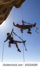 Climbing Team Struggle To The Summit Of A Challenging Rock Mountain.