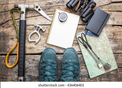 Climbing Tools With Boots And Notebook On Wooden Background. Ice Axe, Nuts, Compass, Mountain Boots And Map Lying On Wood Board