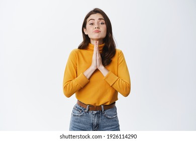 Clingy Cute Woman Asking For Help, Begging You, Holding Hands In Pray With Cute Face, Need Favour, Say Please While Standing Against White Background.