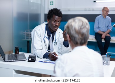 Clinic Doctor Presenting Retired Woman Recovery Program And Diagnosis Report. Senior Patient Discussing With Hospital Physician Specialist About Illness Report And Treatment Schedule