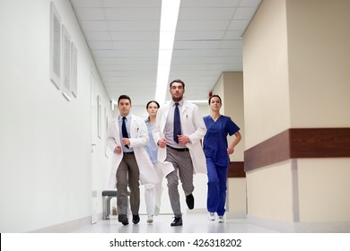 clinic, people, health care and medicine concept - group of medics running along hospital