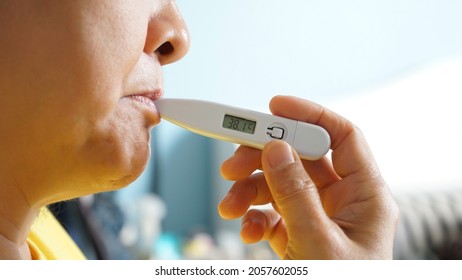 Clinical Digital Oral Thermometer Is Placed In The Mouth Under The Tongue And Showing Temperature 38.1 Degrees Celsius. Asian Adult Who Have A Fever Using Axillary Thermometer. Health Care Content.