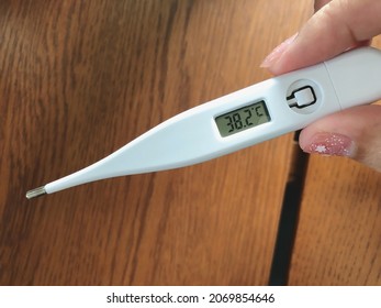 Clinical Digital Oral Thermometer Showing Temperature 38.2 Degrees Celsius. Asian Adult Who Have A Fever Using Axillary Thermometer. Health Care Content, Coronavirus Disease Or COVID-19 Theme.