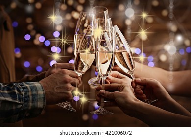 Clinking glasses of champagne in hands on bright lights background with snow effect - Powered by Shutterstock