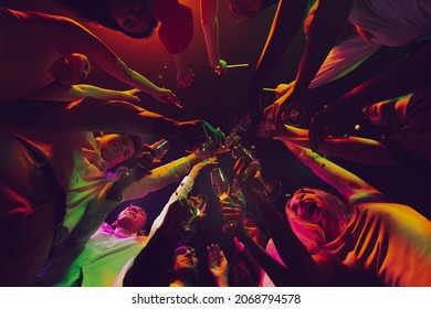 Clinking glasses. Night lifestyle. Group of young, active people at the night club, party dancing in neon, drinking cocktails. Concept of party, fun, holiday, relaxation, meeting Copy space for ad - Powered by Shutterstock