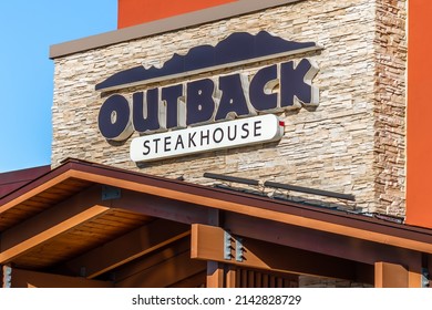 Clinton Twp., MIUSA - October 5, 2020:  Horizontal, medium closeup of "Outback Steakhouse" exterior facade brand and logo signage, above entrance, on a bright sunny day with blue sky.
