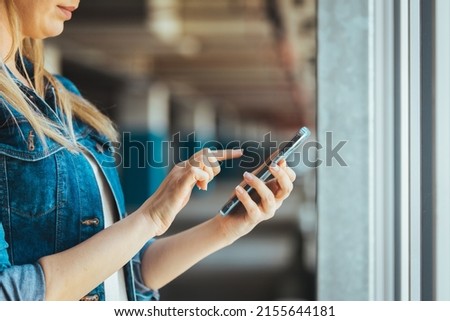 A clip shot of a beautiful young woman using a smartphone. The woman uses a smartphone in the parking lot, exchanges messages or browses social networks.