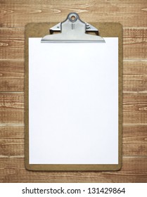 Clipboard With A Blank Sheet Of Paper On Wooden Table