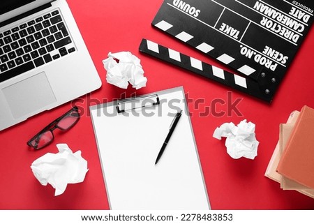 Clipboard with crumpled paper, laptop and movie clapper on red background