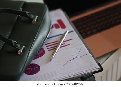 Clipboard Documents And Ballpoint Pen Lying On Open Green Laptop Bag Closeup