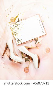 Clipboard and Female shoes with golden decorations. Flat lay, top view trendy holiday concept.   