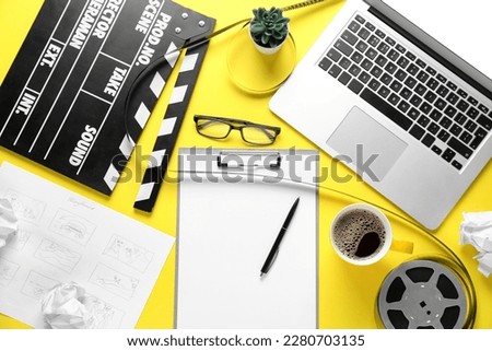 Clipboard with movie clapper, film reel, cup of coffee and laptop on yellow background