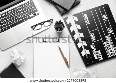 Clipboard with movie clapper, plant, eyeglasses and laptop on white background