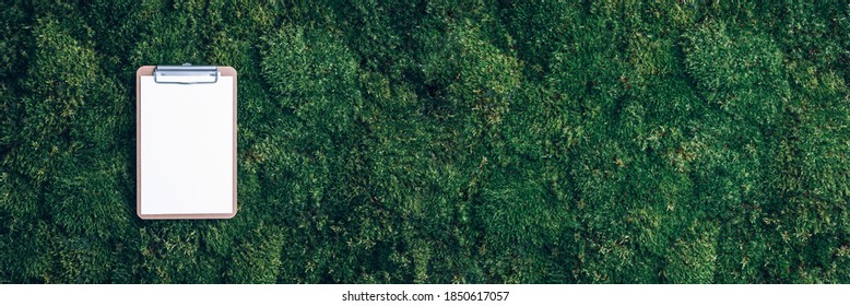 Clipboard, Paper, Pen On Green Grass, Moss Background. Copy Space. Top View. Office Mock Up, Remote Job. Wild Nature, Ecology Concept. Summer Forest. Sustainable, Organic, Zero Waste Lifestyle.