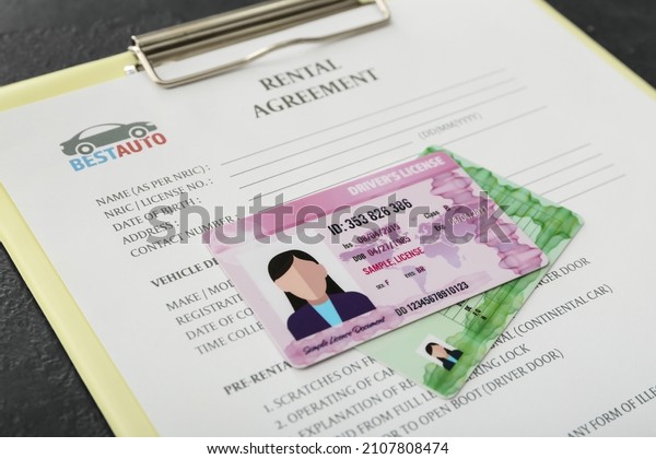 Clipboard with rental agreement and driver\
licenses, closeup