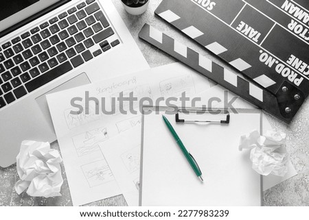 Clipboard with storyboard, laptop and movie clapper on grunge background