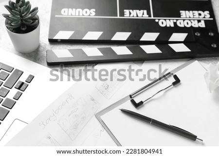 Clipboard with storyboard, laptop and movie clapper on grunge background, closeup