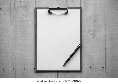 Clipboard with white sheet on wood background. Top view. Mock up fir word.