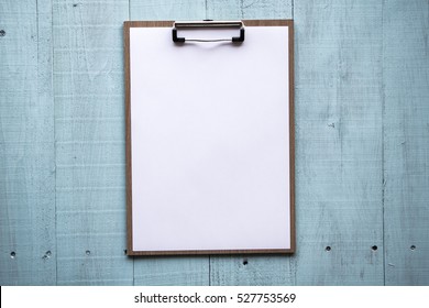 Clipboard with white sheet on wood background. Top view. mock up for word.