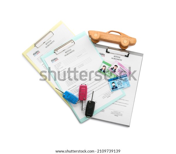 Clipboards with rental agreement, car\
keys, driver licenses and wooden car on white\
background