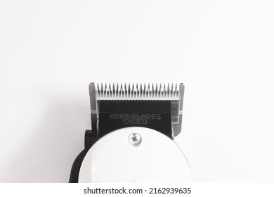 Clipper Blade Focused On White Background And A Blurred Message As Keep Blades Oiled Written On The Black Plastic Part.