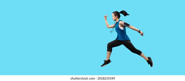 Clipping path young Asian active woman running and jumping isolated in studio on banner light blue color background. Isolated healthy women in sportswear workout sprinting.