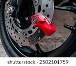 Clise up red disc brake padlock installed on a motorcycle disc brake