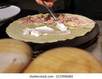 Cloae Up A Hand Holding Spoon Smearing Cream On Ham And Mushroom Crepe