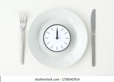Clock with 12 o'clock on white plate with fork and knife - Shutterstock ID 1758342914