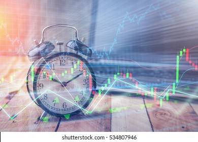 Clock alarm with stock graph chart in laptop screen background.Time,stock market,business success and investment concept.