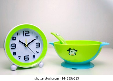 A Clock And Baby Suction Bowl. Its A Baby Feeding Time Concept.