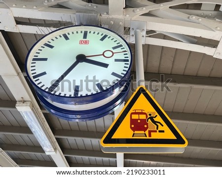 Clock and caution sign, do not fall off a platform 